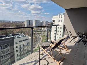 einen Balkon mit einem Stuhl und Stadtblick in der Unterkunft APARTAMENT W CHMURACH- 15 PIĘTRO OSIEDLE TYSIĄCLECIA- parking w hali garażowej, wielki taras z widokiem na zachód słońca in Kattowitz