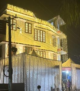 AlleppeySreeragam residency cherthala的一座黄色的大建筑,前面有白色窗帘