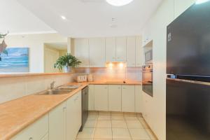 a kitchen with white cabinets and a stainless steel refrigerator at Ocean Tower Unit 1104 - Twin Towns in Tweed Heads
