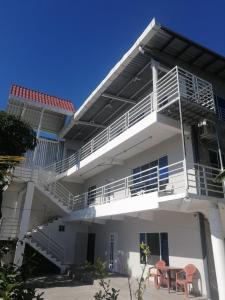 Dieses weiße Haus verfügt über einen Balkon und einen Tisch. in der Unterkunft Apartamento Familiar 3 con 3 habitaciones 4 camas más litera in San Salvador + 21 Fotos