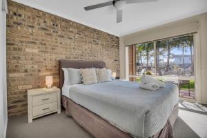 a bedroom with a brick wall and a large bed at Lakeside Apartments - Fishpen in Merimbula