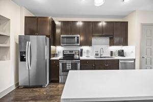 フリスコにあるSerene Frisco Apt with Pool and Gymのキッチン(木製キャビネット、ステンレス製の冷蔵庫付)
