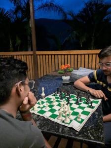 two men sitting at a table playing a game of chess at CharDara Agrotourism & FarmStay in Mahabaleshwar