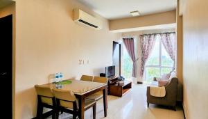 a living room with a dining room table with chairs and a room with a window at Minimalist 1BR Mactan Newtown Suite w Pool in Lapu Lapu City
