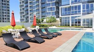 a row of chairs and umbrellas next to a pool at Minimalist 1BR Mactan Newtown Suite w Pool in Lapu Lapu City