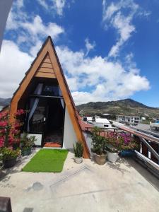a small house with a pointed roof with plants at Homestay Begonia Syari'ah in Dieng