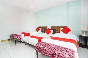 three beds in a room with red and white pillows at King One Suvarnabhumi in Bangkok
