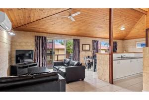 a living room with black leather furniture and a kitchen at Discovery Parks - Bunbury Foreshore in Bunbury