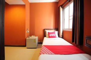 a bedroom with orange walls and a bed with a red pillow at Pannee Lodge Khaosan - SHA Plus in Bangkok