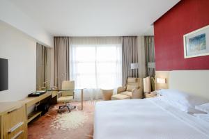 a hotel room with a bed and a desk and chair at Four Points by Sheraton Qingdao, Chengyang in Qingdao