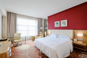 a bedroom with a large bed and a red wall at Four Points by Sheraton Qingdao, Chengyang in Qingdao