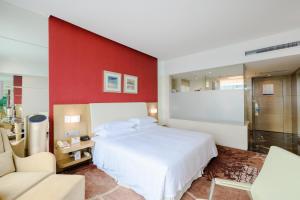 a bedroom with a white bed and a red wall at Four Points by Sheraton Qingdao, Chengyang in Qingdao