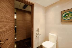 a bathroom with a toilet and a wooden door at Four Points by Sheraton Qingdao, Chengyang in Qingdao
