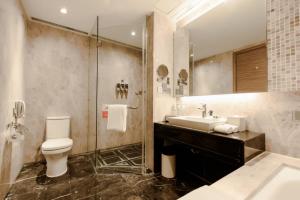 a bathroom with a sink and a toilet and a mirror at Four Points by Sheraton Qingdao, Chengyang in Qingdao