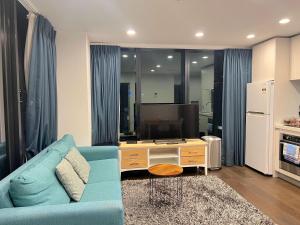 a living room with a blue couch and a tv at Gorgeous Seaview and Harbour View 2 BDR 2 BTH Apartment in Auckland +48 photos
