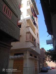 a tall building with a balcony on a street at شقة مفروشة للايجار فى دمياط القديمة الشارع الحربى in Dumyāţ