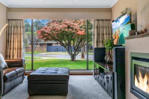 伊丘卡Jensen House - Retro Style with a modern update的带沙发和电视的客厅以及树。