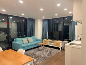 a living room with a blue couch and a tv at Gorgeous Seaview and Harbour View 2 BDR 2 BTH Apartment in Auckland
