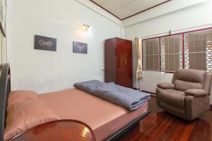 a small room with a bed and a chair at OYO 75469 Baan Kong Hostel in Ban Talat Takua Pa