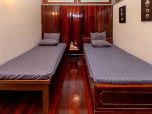 two twin beds in a room with wood floors at OYO 75469 Baan Kong Hostel in Ban Talat Takua Pa