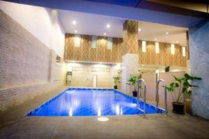 a large swimming pool in a building with a blue floor at Collection O JA Siam City in Pattaya