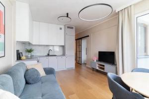 a living room with a blue couch and a kitchen at JetSet Airport Apartment in Warsaw