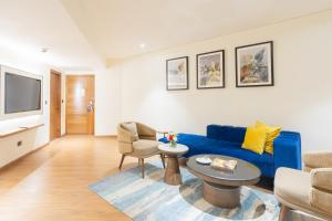 a living room with a blue couch and a table at Golden Tulip Jaipur City Center in Jaipur