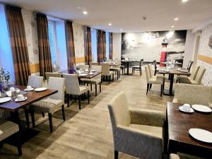 un ristorante con tavoli e sedie e il dipinto di un faro di Hotel Up Diek a Carolinensiel
