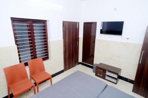 a room with two chairs and a table and a tv at Royal Lodge in Nāgercoil