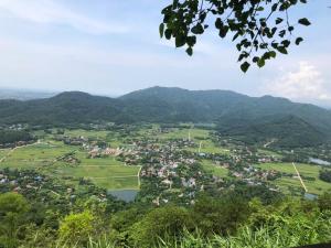 a village in a valley with mountains in the background at Authentic Mia Rooftop Mountains view with egg coffee in Sóc Sơn