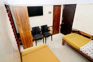 a room with a bed and chairs and a tv at Royal Lodge in Nāgercoil +1 photo