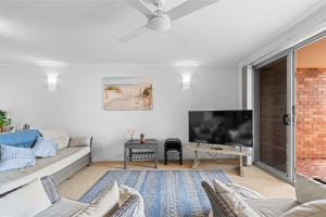 Una sala de estar con un sofá y un televisor. en Seaside Holiday Apartments Tugun, en Gold Coast