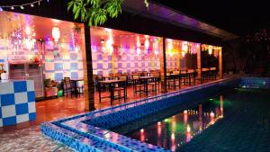 a restaurant with a pool and tables and lights at SaBai Backpacker Hostel in Vang Vieng