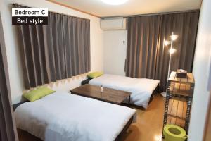 Una habitación con dos camas y una mesa y una ventana. en f life house, en Koriyama 75 fotos más