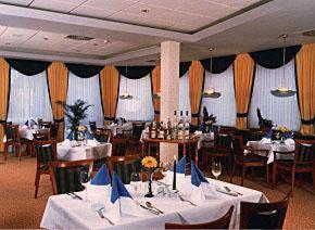 ein Esszimmer mit weißen Tischen, Stühlen und einem Tischler in der Unterkunft Hotel Domicil Schönebeck in Schönebeck