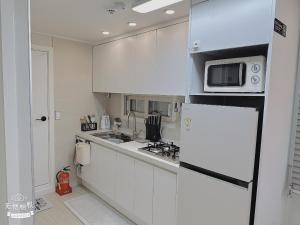 a white kitchen with a microwave and a refrigerator at Jaha 79 in Seoul