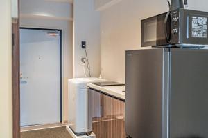 a kitchen with a stainless steel refrigerator and a microwave at Apartment Hotel 11 Shinsaibashi 5 in Osaka