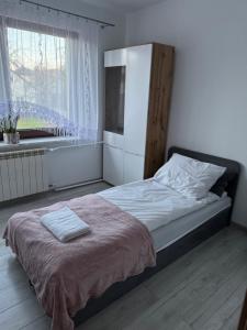 a bedroom with a bed with a refrigerator and a window at Oaza Spokoju in Augustów