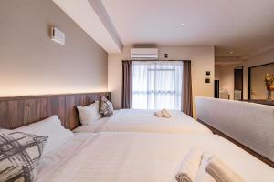 two beds in a room with a window at Apartment Hotel 11 Shinsaibashi 5 in Osaka +25 photos