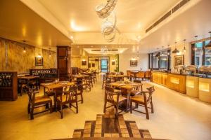 un ristorante con tavoli e sedie in legno in una stanza di Hotel The Grand Manali - A River and Mountain View Resort, Manali #Private Parking #GYM a Manāli