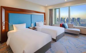 a hotel room with two beds and a couch and a window at Novotel Atlantis Shanghai - Enjoy our great-valued breakfast in our rooftop revolving restaurant with a stunning river view & utilize our FREE self-serviced laundry in Shanghai