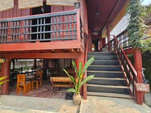 a staircase leading to a house with a table and chairs at บ้านปู่ทอง Grandpa's House in Chiang Khan