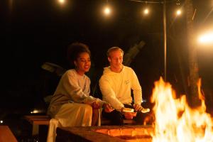 Un uomo e una donna seduti accanto al fuoco di Bobocabin Umarato, Sumba a Waikabubak