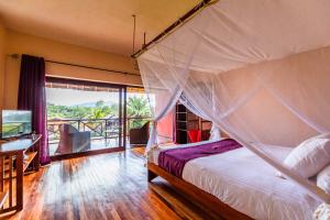 a bedroom with a canopy bed and a balcony at Lac Hôtel Sahambavy in Ambatomalama +19 photos