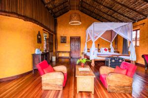 a living room with a bed and a table and chairs at Lac Hôtel Sahambavy in Ambatomalama