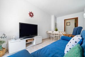 Una sala de estar con un sofá azul y un televisor de pantalla plana. en Apartamento Familiar en la Pineda, en La Pineda