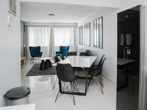 a dining room with a white table and blue chairs at Romilly Beachfront 92 in Strand