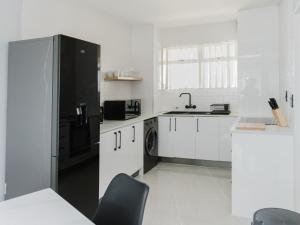 a kitchen with a black refrigerator and white cabinets at Romilly Beachfront 92 in Strand