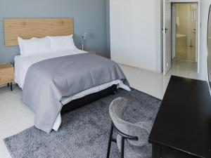 a bedroom with a bed and a table and a chair at Romilly Beachfront 92 in Strand