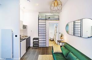 Una sala de estar con un sofá verde y una cocina. en Studio cosy avec mezzanine, bien équipé, Caluire, en Caluire-et-Cuire 6 fotos más